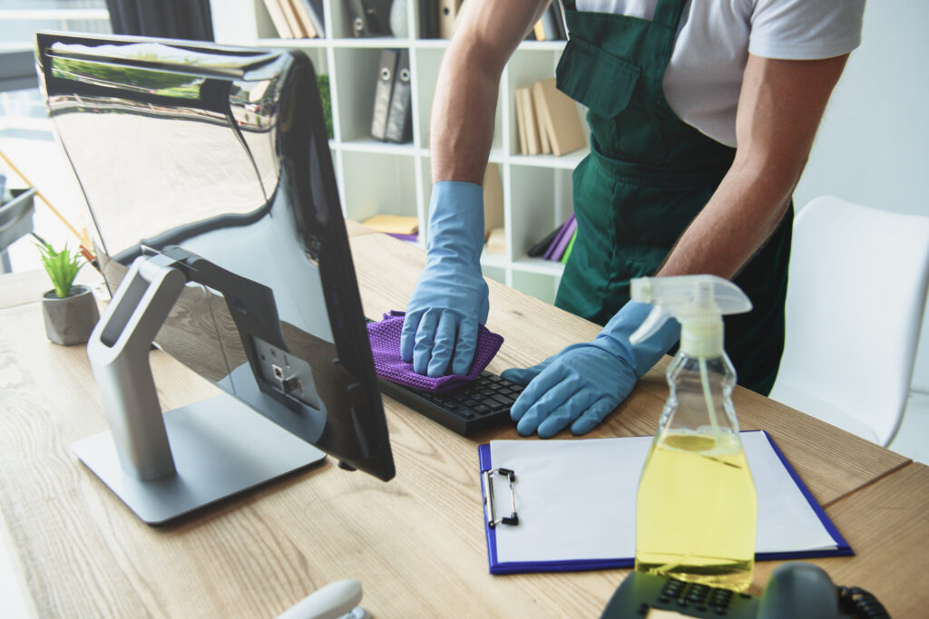 photo recadrée d'un nettoyeur professionnel dans des gants en caoutchouc nettoyant le clavier de l'ordinateur au bureau