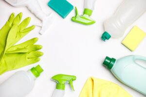 Bouteilles avec agent de nettoyage écologique, éponges de nettoyage vertes et gants posé sur une table blanche